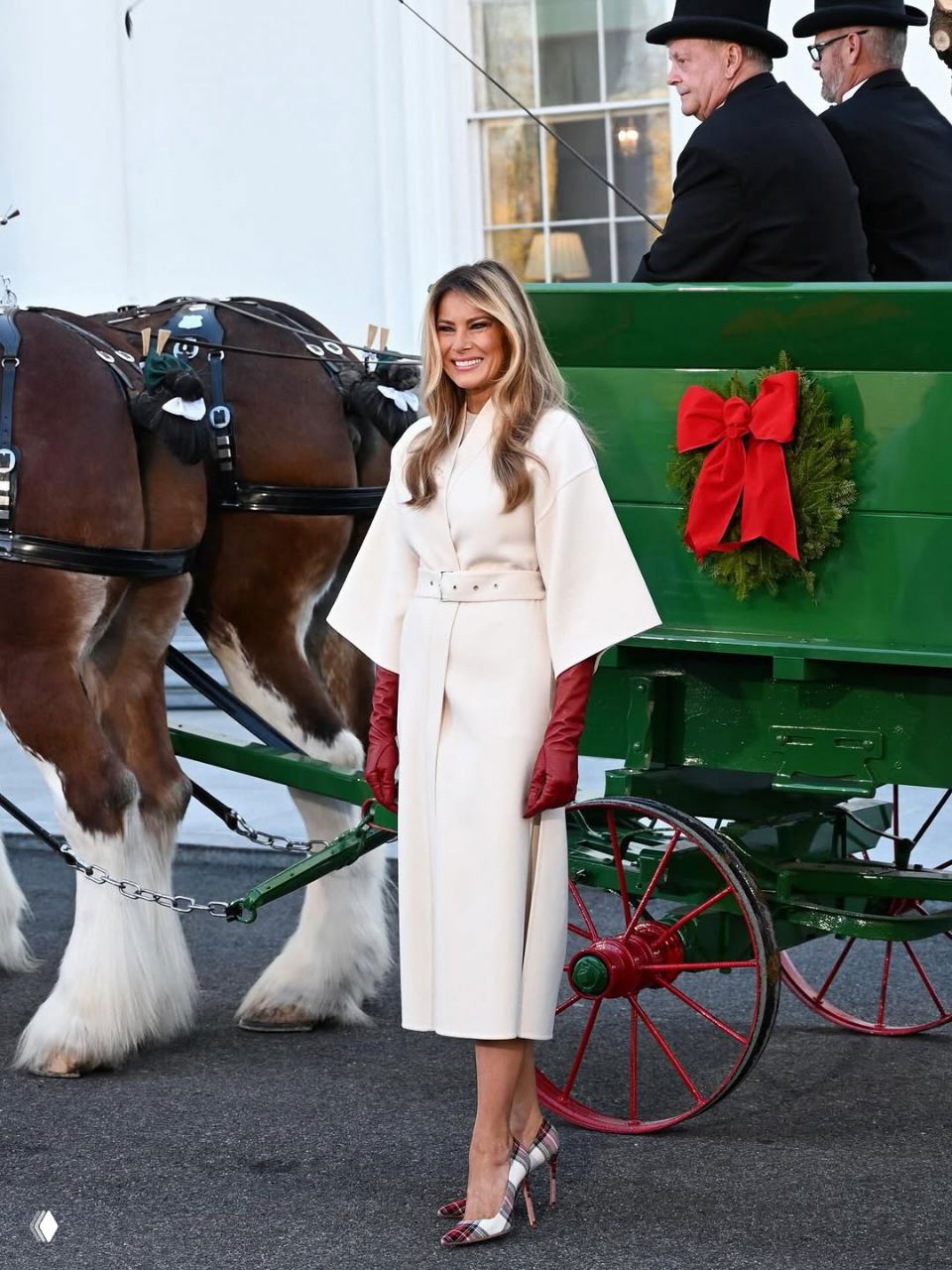 Мелания Трамп у праздничной повозки у Белого дома в светлом пальто Dior, красные перчатки и туфли Manolo Blahnik на фоне украшенной ленты рождественской телеги