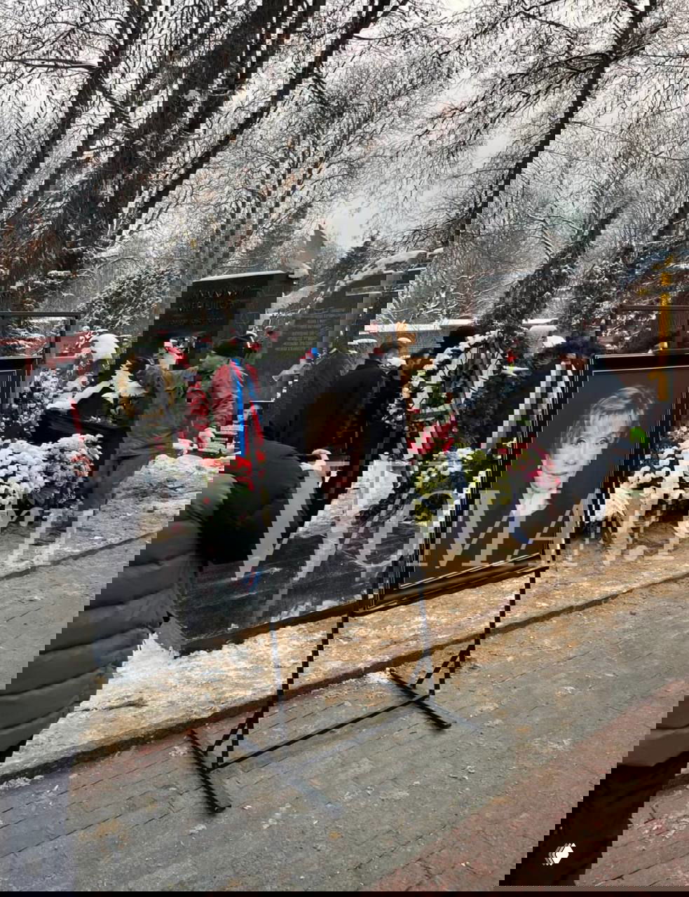 Портрет на стенде у могилы, рядом венки и цветы, снежный пейзаж и люди на Новодевичьем кладбище во время похорон.