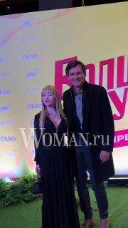 Филипп Янковский вместе с гостьей на фоне праздничного баннера премьеры «Волшебный участок» в Мосфильме; виден водяной знак WOMAN.ru.