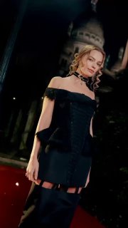 Крупный план Марго Робби в черном платье Thom Browne на фоне архитектуры Парижа и вечернего освещения во время афтепати после премьеры «Грозового перевала».