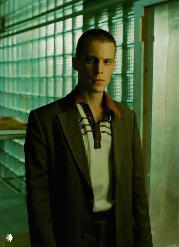 Режиссёрский или студийный портрет Ивана Янковского в строгом образе на фоне зелёного стеклянного интерьера, драматическое освещение.