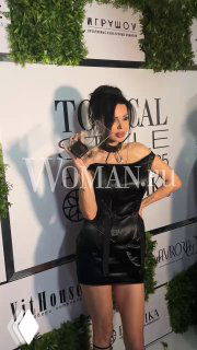 Кадр: Оксана Самойлова в чёрном мини-платье с наградой «Икона стиля» на фоне баннера Topical Style Awards.