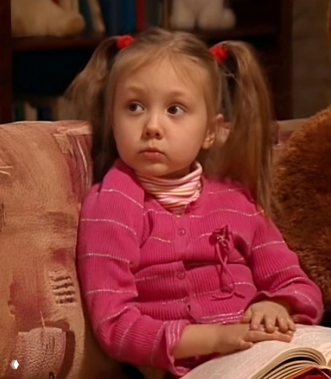 Кадр из сериала «Папины дочки»: маленькая Пуговка с хвостиками в розовом кардигане, задумчивый взгляд, домашняя сцена из телесериала.