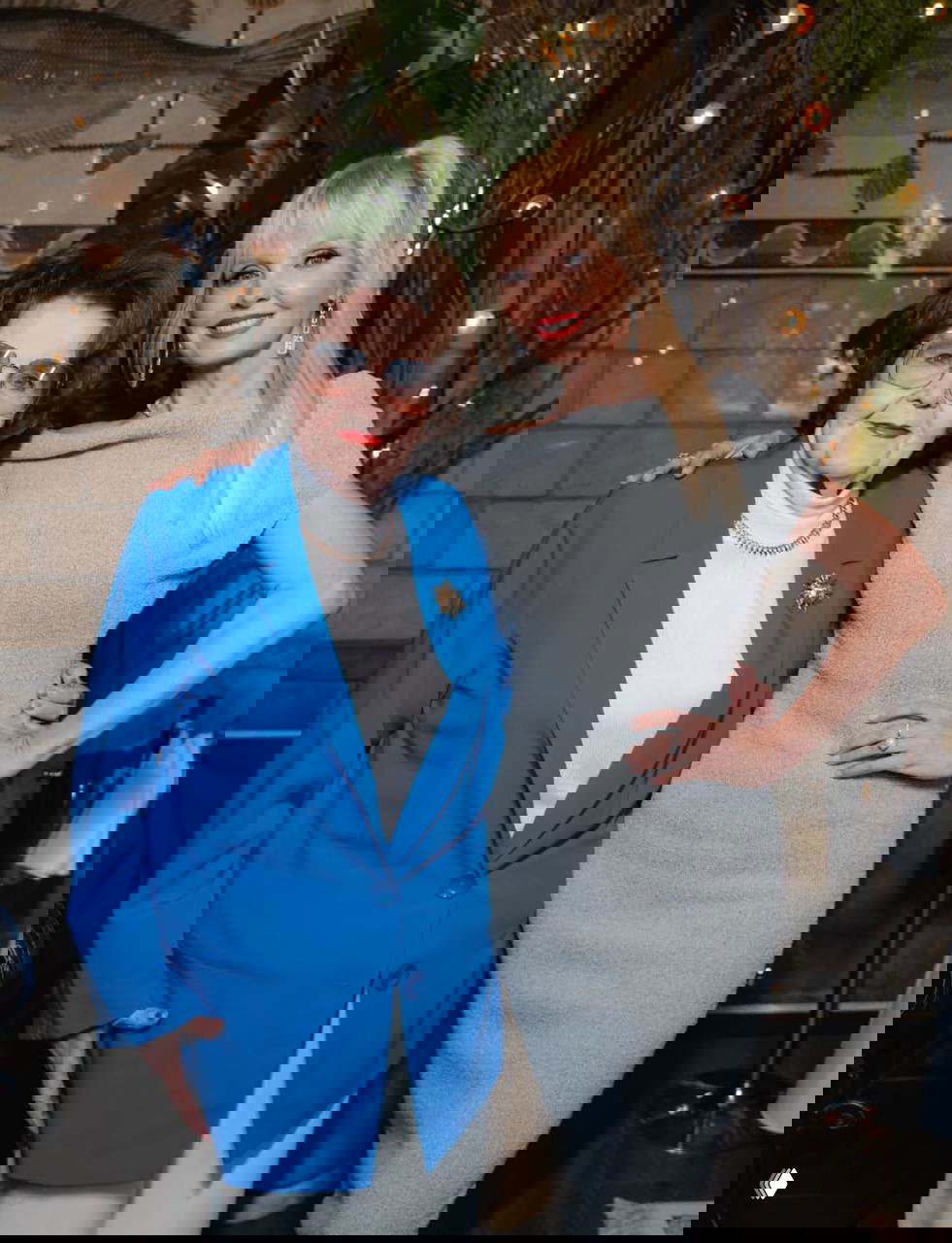 Две женщины разных поколений позируют в интерьере: пожилая дама и более молодая женщина улыбаются рядом друг с другом, тёплый семейный портрет.