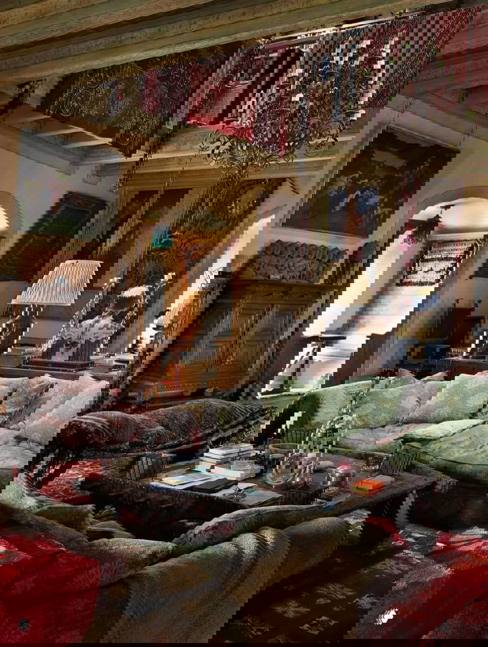 Просторная гостиная замка Килко с высоким балочным потолком, антикварными коврами, диванами и массивным центральным столом, богатый эклектичный интерьер.