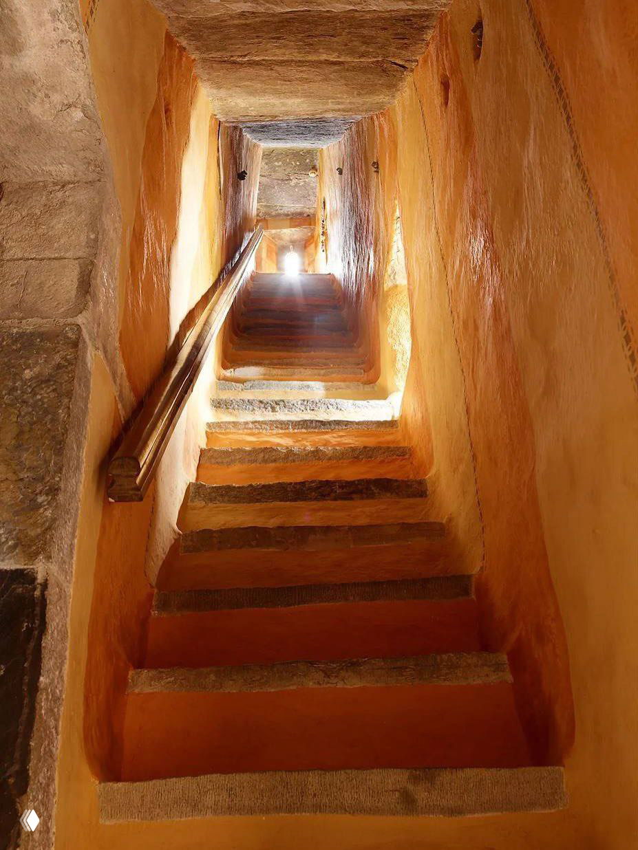 Узкая каменная лестница замка Килко с глубокими ступенями и тёплым светом в конце коридора — характерный элемент средневековой планировки.