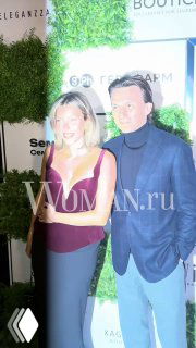 Влад Топалов и Регина Тодоренко позируют вместе на фотозоне премии MODA Topical: пара в вечерних нарядах на фоне зелёной стены с логотипами.