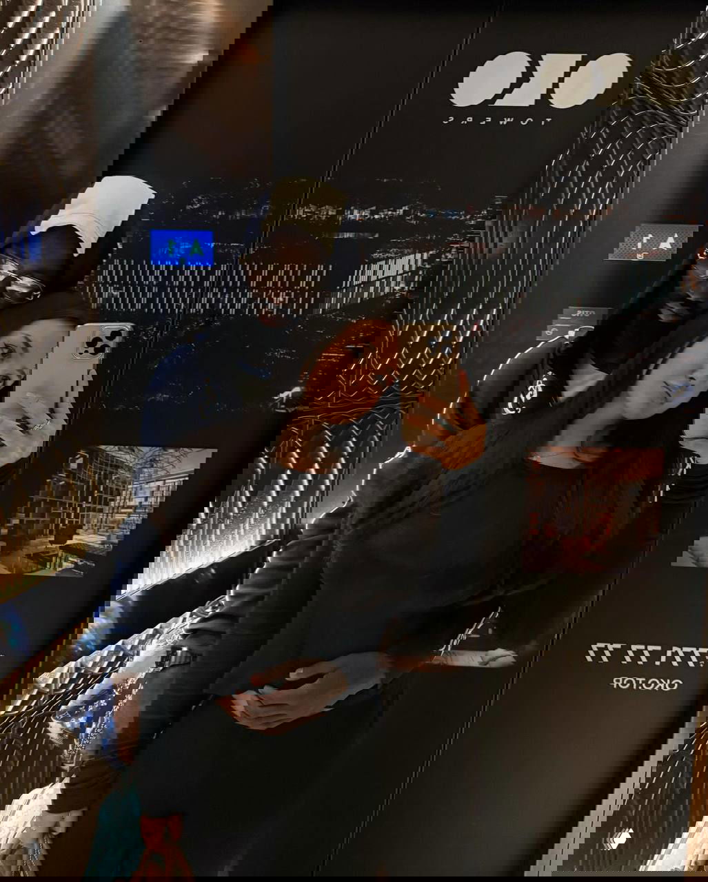 Селфи в лифте: мужчина обнимает Нику Черемисинову, рука на талии, видно зеркало и ночной городской вид за стеклом.