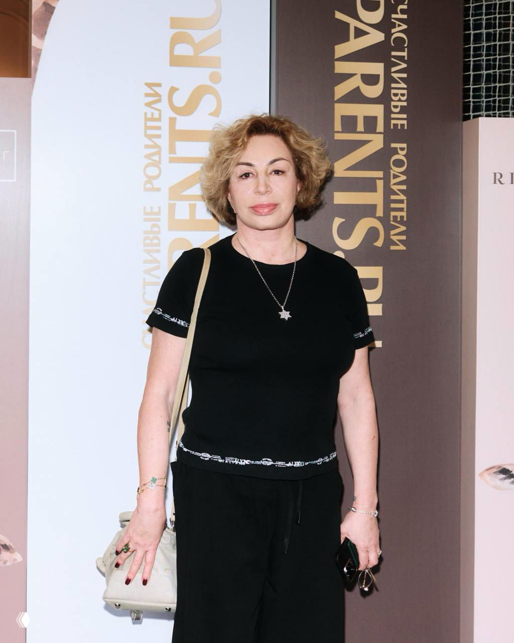 Валентина Иванова позирует на фоне баннера «Parents.RU»: портретный снимок на светлом фоне с надписями мероприятия и деловым настроем.