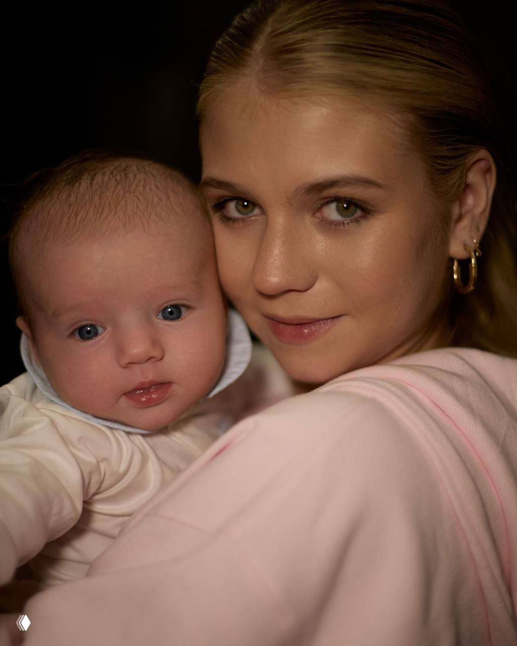 Портрет Саши Трусовой, держащей на руках маленького сына Мишу — тёплое студийное фото, крупный план лиц матери и младенца.