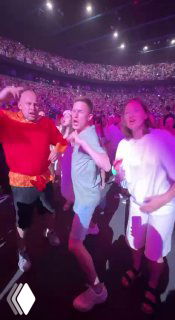 Зал концерта с толпой зрителей и несколькими людьми у сцены при ярких прожекторах — иллюстрация популярности артистов и корпоративных шоу.