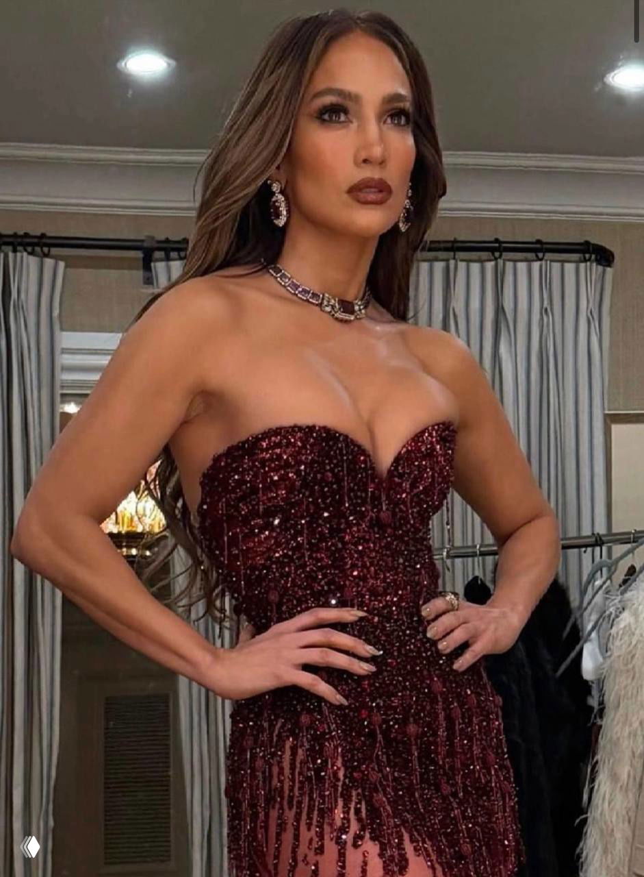 Крупный план Дженнифер Лопес: корсетное декольте, украшения и макияж; видны мелкие детали расшитого кристаллами бордового платья
