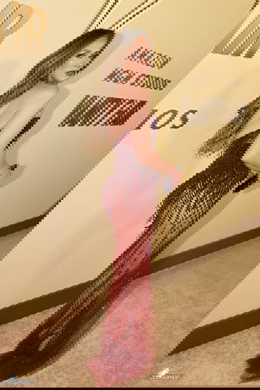 Профильный кадр Дженнифер Лопес у фотостены Vanity Fair: прозрачный низ платья, расшитый бисером, видно силуэт и туфли в тон