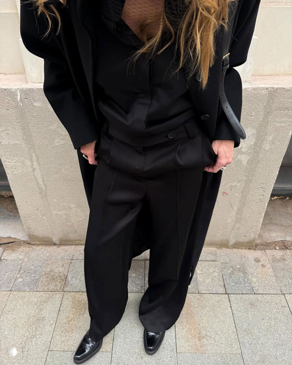 Кадр по пояс и низ: черные брюки, рубашка и пальто, руки с аксессуарами, детали кроя и фактура ткани в тотал-блэк луке.