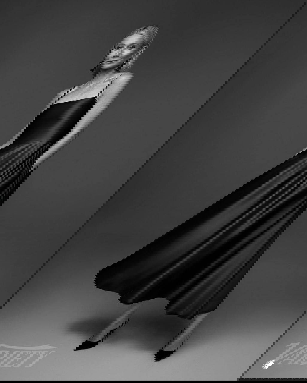 Полноразмерный монохромный снимок: Гвинет Пэлтроу в элегантном чёрном платье позирует в студии, акцент на силуэт и фактуру ткани