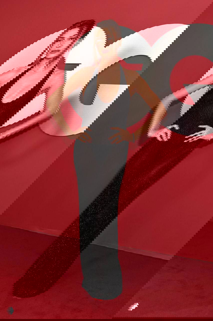 Хейли Бибер в полупрозрачном чёрном платье Gucci на красной дорожке GQ Men of the Year 2025, полный рост, элегантная поза и украшения.