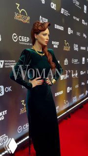 Настасья Самбурская в тёмно‑зелёном платье на красной дорожке премии «Золотой Граммофон», позирует на фоне бренд-волла с логотипами.