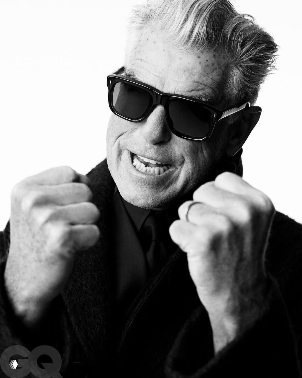 Крупный чёрно‑белый портрет мужчины в тёмных очках, динамичная жестикуляция руками, акцент на эмоциях и текстуре кожи в студийной съёмке.