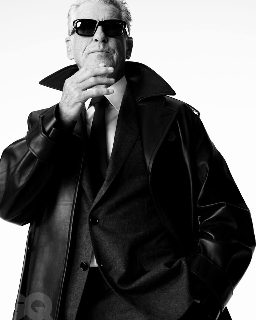 Студийный чёрно‑белый кадр: мужчина в кожаном плаще и костюме, строгая композиция и мужская элегантность в журнальном стиле.