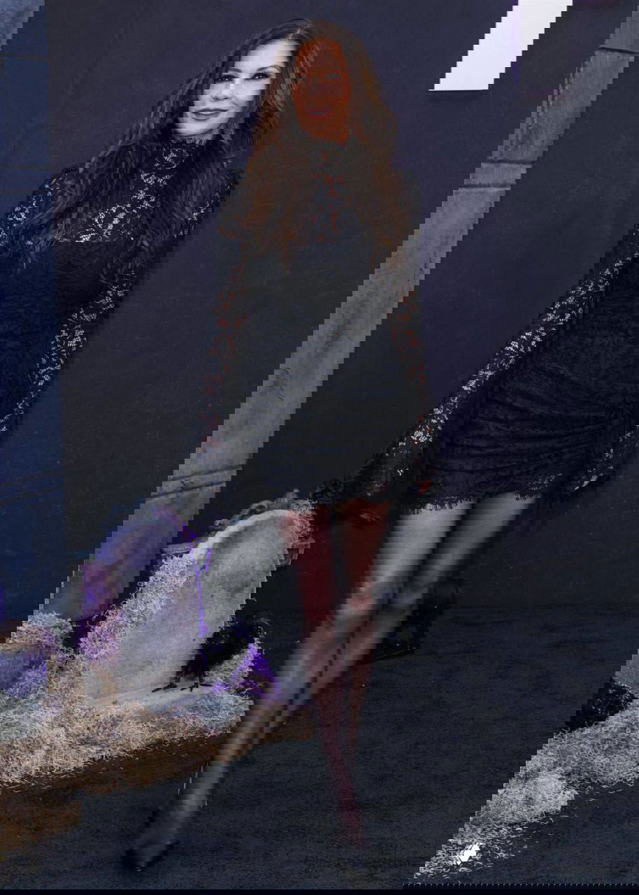 Кэтрин Зета‑Джонс в черном кружевном платье на красной дорожке мероприятия в поддержку «Уэнсдей» в Лос‑Анджелесе, фон с декором и памятниками.