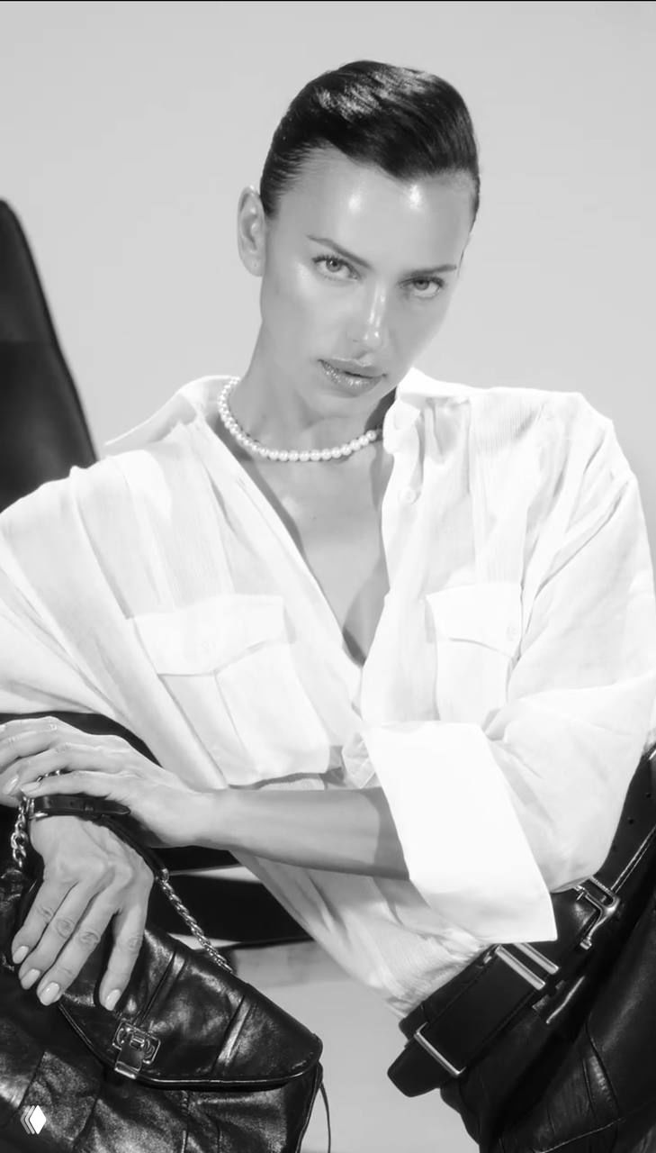 Портретная черно‑белая съёмка модели в белой рубашке и жемчужном ожерелье — стильный кадр из рекламной фотосессии.