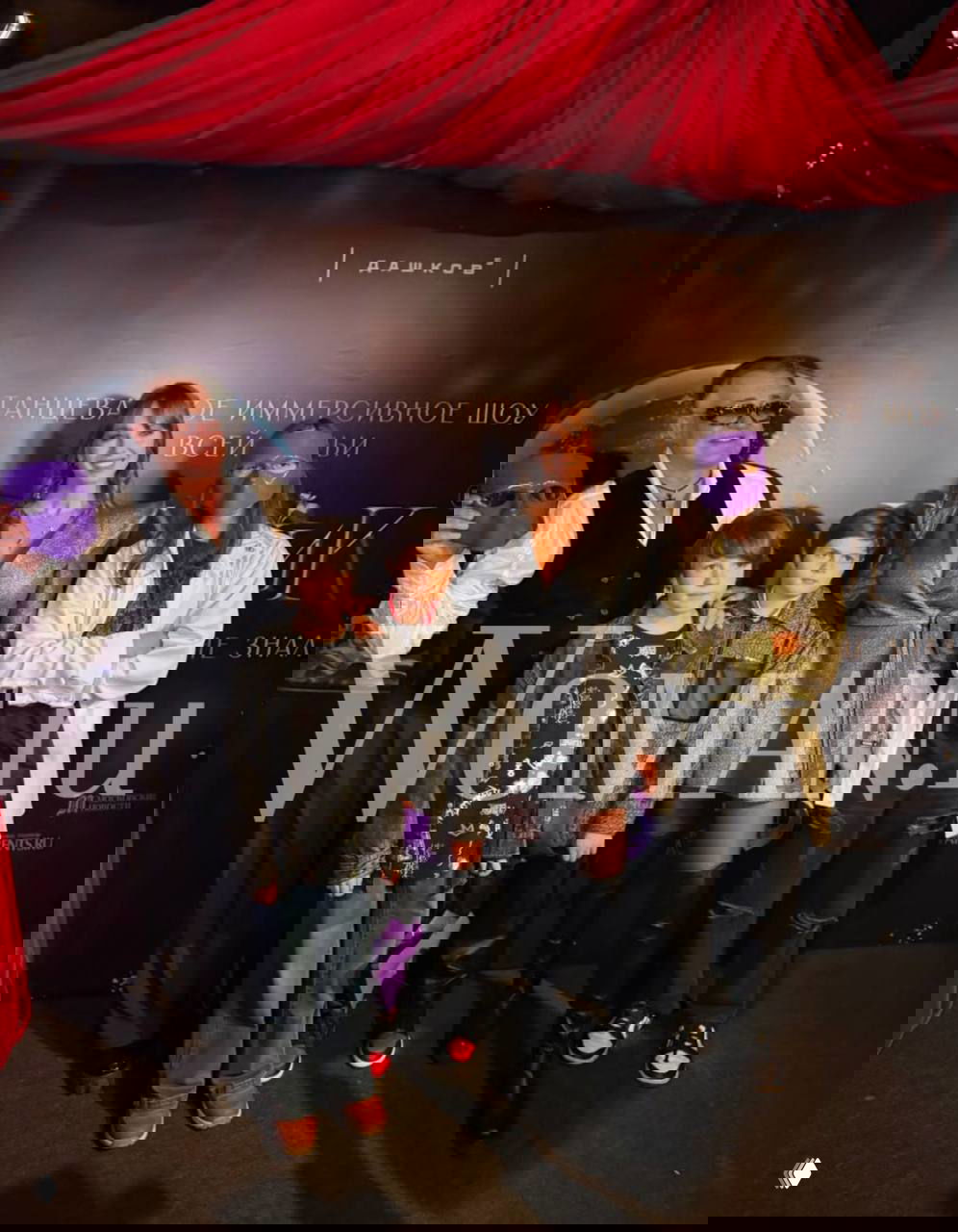 Семья Дибровых позирует у баннера иммерсивного театра «Особняк Дашков 5»: Полина в мини-платье, дети и взрослый в фиолетовой маске.