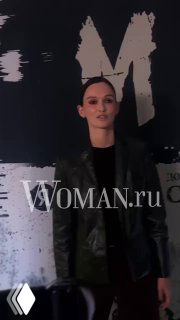 Паулина Андреева в тёмном пиджаке и чёрной рубашке на фоне баннера с логотипом Woman.ru — портретный кадр с мероприятия