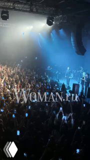 Сцена Arbat Hall во время концерта Эмре Алтуга: тысячи зрителей с поднятыми телефонами, артист на сцене и синяя подсветка зала.