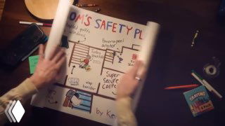 Руки держат лист с нарисованным сторибордом и схемой на рабочем столе; видны маркеры, скотч и блокнот.