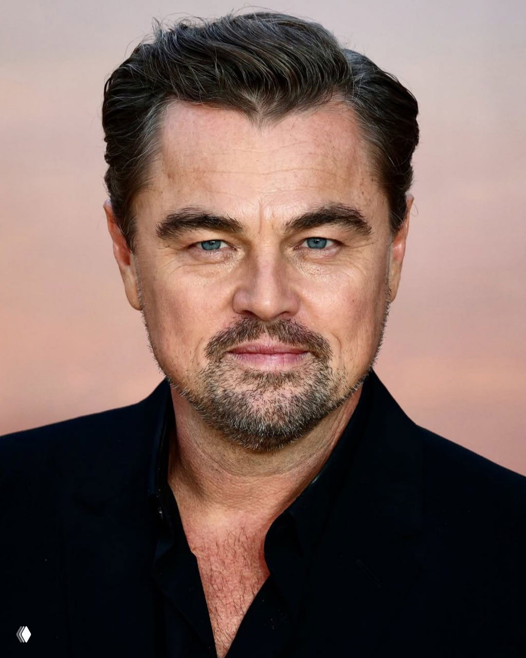 Крупный портрет Леонардо ДиКаприо: детализированный снимок лица с голубыми глазами, лёгкой щетиной и сдержанной улыбкой на нейтральном фоне.