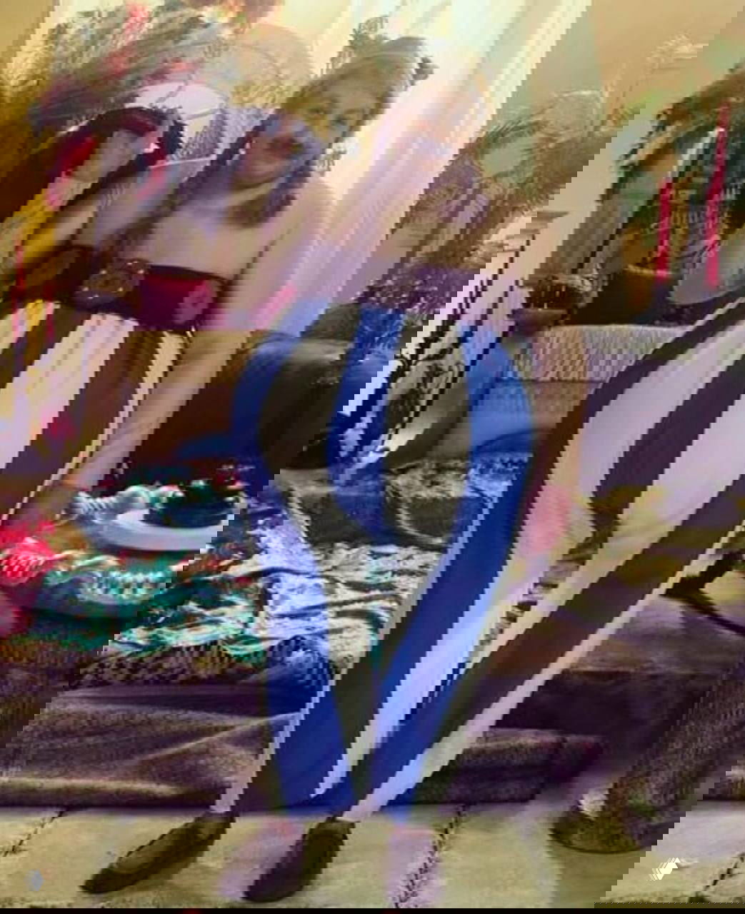 Человек в ярком сценическом костюме на фоне декоративных элементов, образ театральный и комичный.