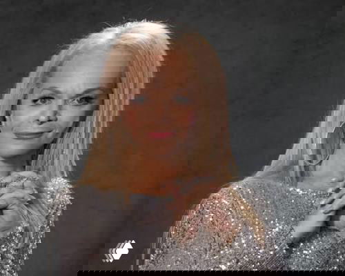 Портрет артистки в серебристом платье и крупных серьгах на однотонном сером фоне, снят по пояс, руки сложены