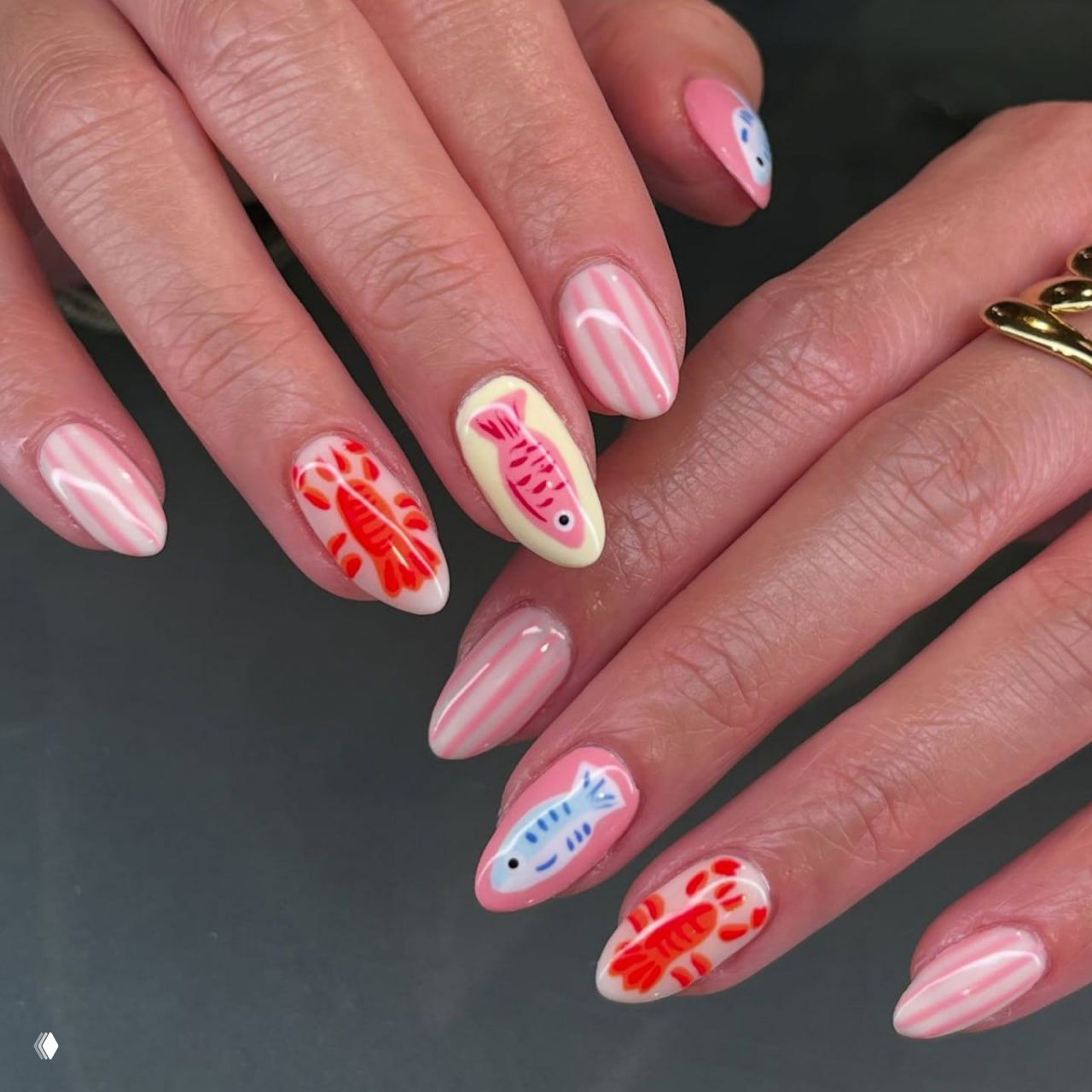 Руки с розово-белым маникюром: полосы, маленькие рыбки и коралловые акценты — игривый летний дизайн ногтей.
