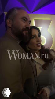 Крупный план Анфисы Чеховой и Александра Златопольского на презентации «ТВ-3»: пара улыбается в камеру, на снимке виден водяной знак Woman.ru и фиолетовая подсветка.