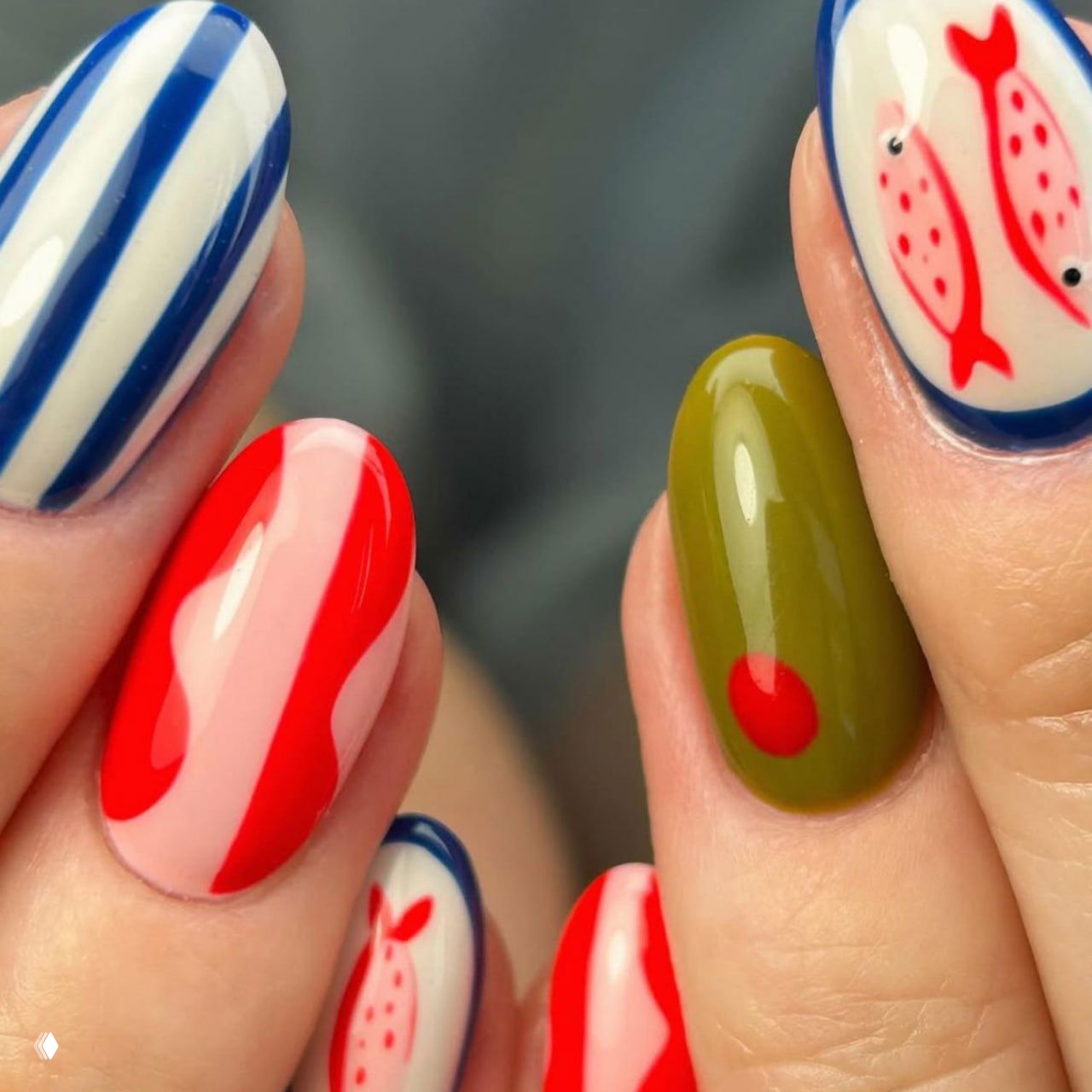 Крупный план разноцветного маникюра: синие полосы, красные волнистые акценты и оливковые элементы с точечным ярким акцентом.
