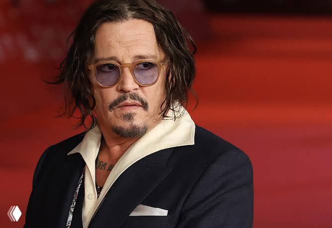Крупный портрет Джонни Деппа на красной дорожке: тёмный пиджак, аккуратная причёска и очки, лицо крупным планом, иллюстративное фото для новости о фильме.