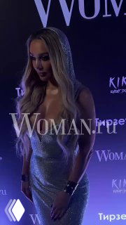 Анна Седокова в блестящем платье на сцене музыкального вечера; видны логотип Woman.ru, фиолетовое освещение и атмосфера шоу