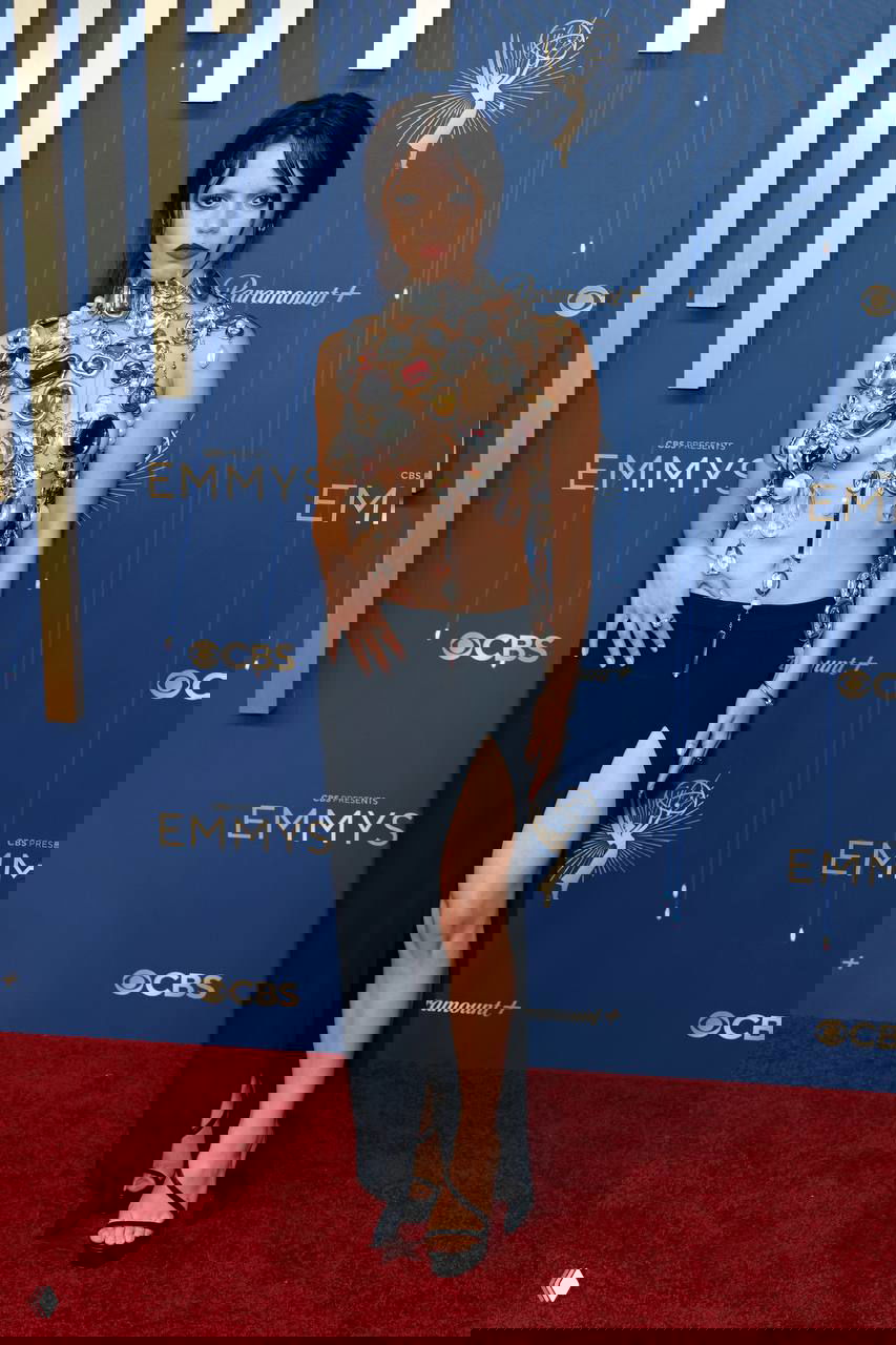 Образ на премьере: открытый топ с крупными декоративными камнями и юбка со шлицем, эффектный макияж и акцент на украшениях, красная дорожка