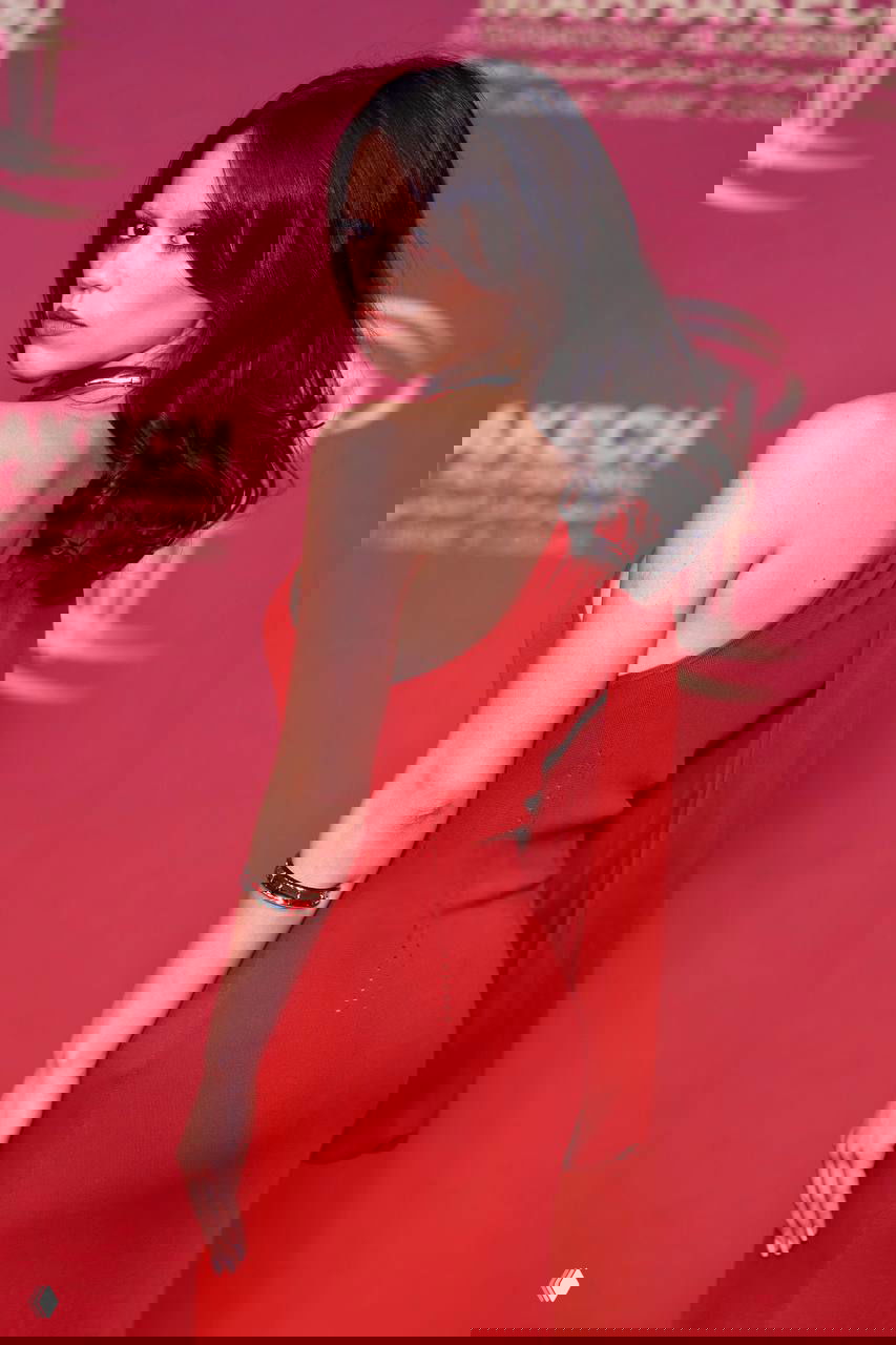 Фотография со спины и полу-поворотом: красное платье и открытая спина на фоне декора красной дорожки Марракеша.