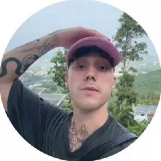 Круглый аватар с портретом молодого человека в кепке на фоне пейзажа города, видны татуировки на шее и расслабленный вид.