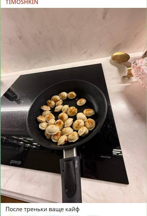 Кадр с кухонной плитой: сковорода с обжаренными пельменями на конфорке, видна часть столешницы и кухонной утвари