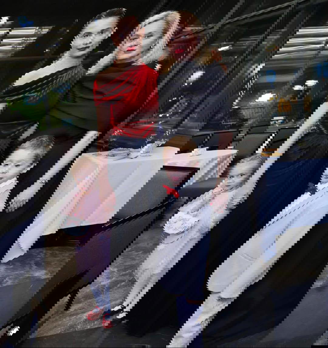 Дети и взрослые в праздничных костюмах на фоне интерьера банкетного зала: семейный момент юбилея.