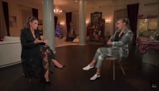 Две женщины в интерьерной студии сидят напротив друг друга во время интервью: видны кресла, колонны и элементы декора, интимная телевизионная обстановка.