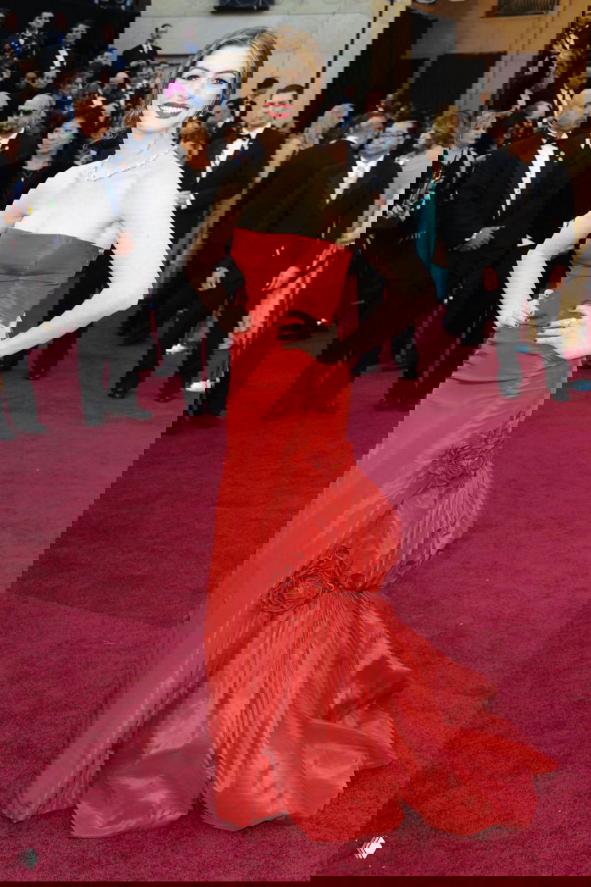 Энн Хэтэуэй в обтягивающем красном платье без бретелей на церемонии, строгий и элегантный образ с минимальными аксессуарами.