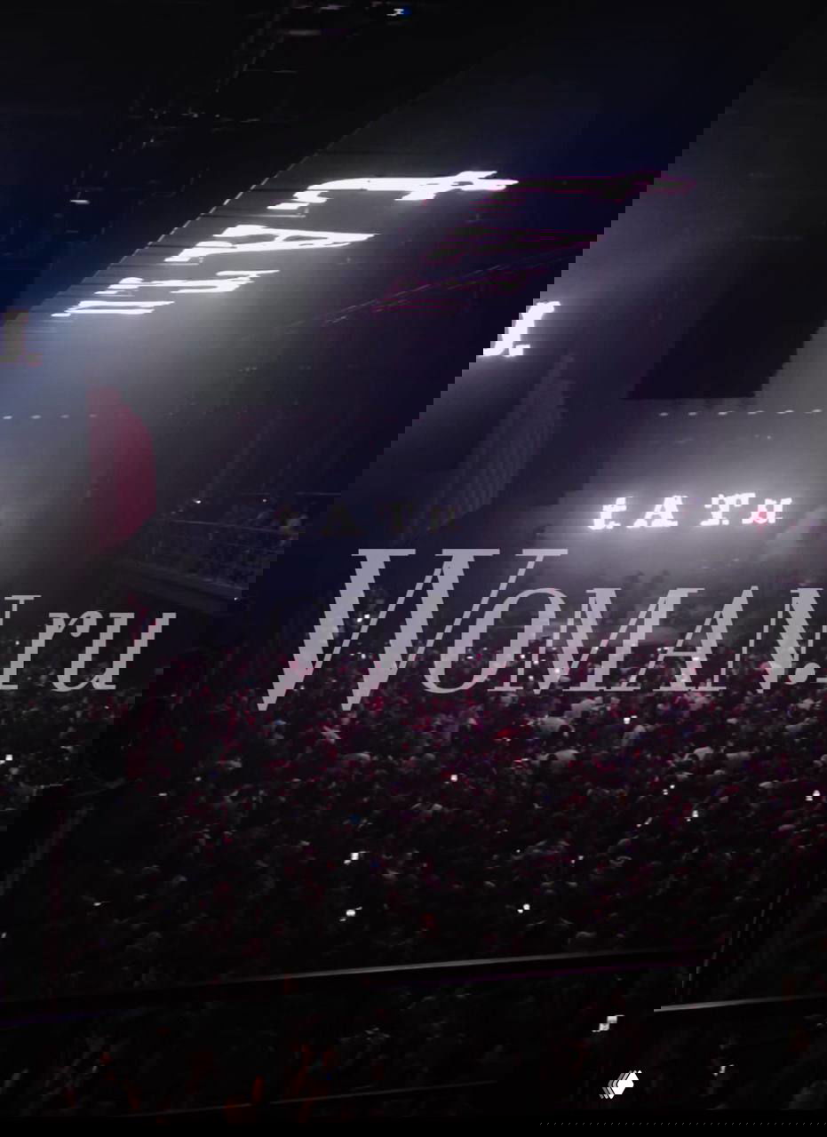 Общий план концертного зала на выступлении «Тату» в Москве: полный зал зрителей, подсветка, проекция названия группы на заднике и большой водяной знак Woman.ru