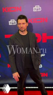 Сергей Гилев позирует на красной дорожке на фоне бренд-волла с логотипами; портретный кадр с водяным знаком Woman.ru