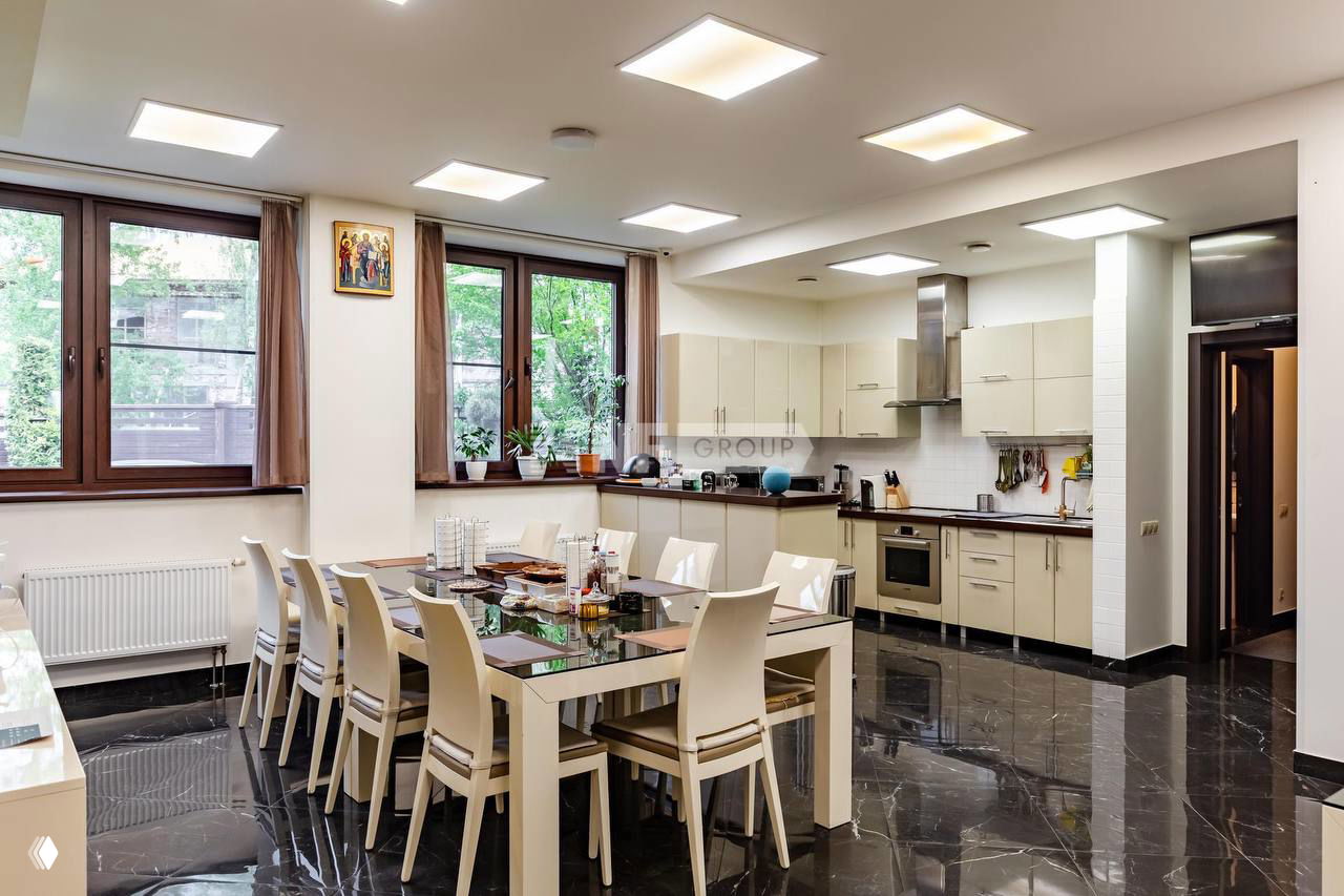 Кухня-столовая с большим столом и современной техникой рядом с окнами, интерьер хозяйственной зоны в одном из выставляемых домов на продажу.