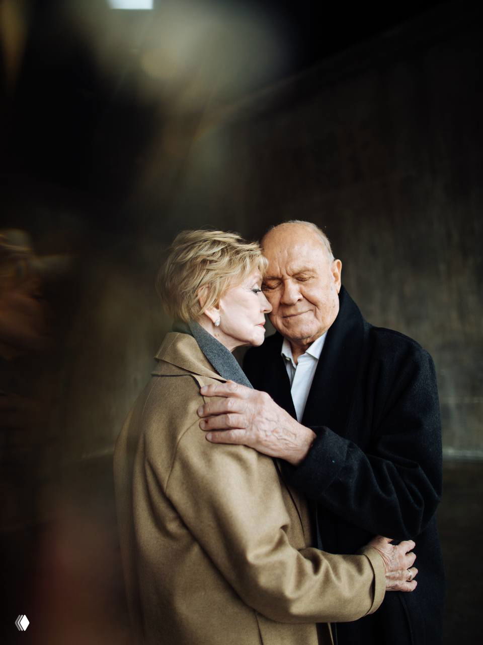 Крупный план пары в объятиях: глаза закрыты, руки на плечах — атмосферный и трогательный кадр, передающий горечь и утешение.