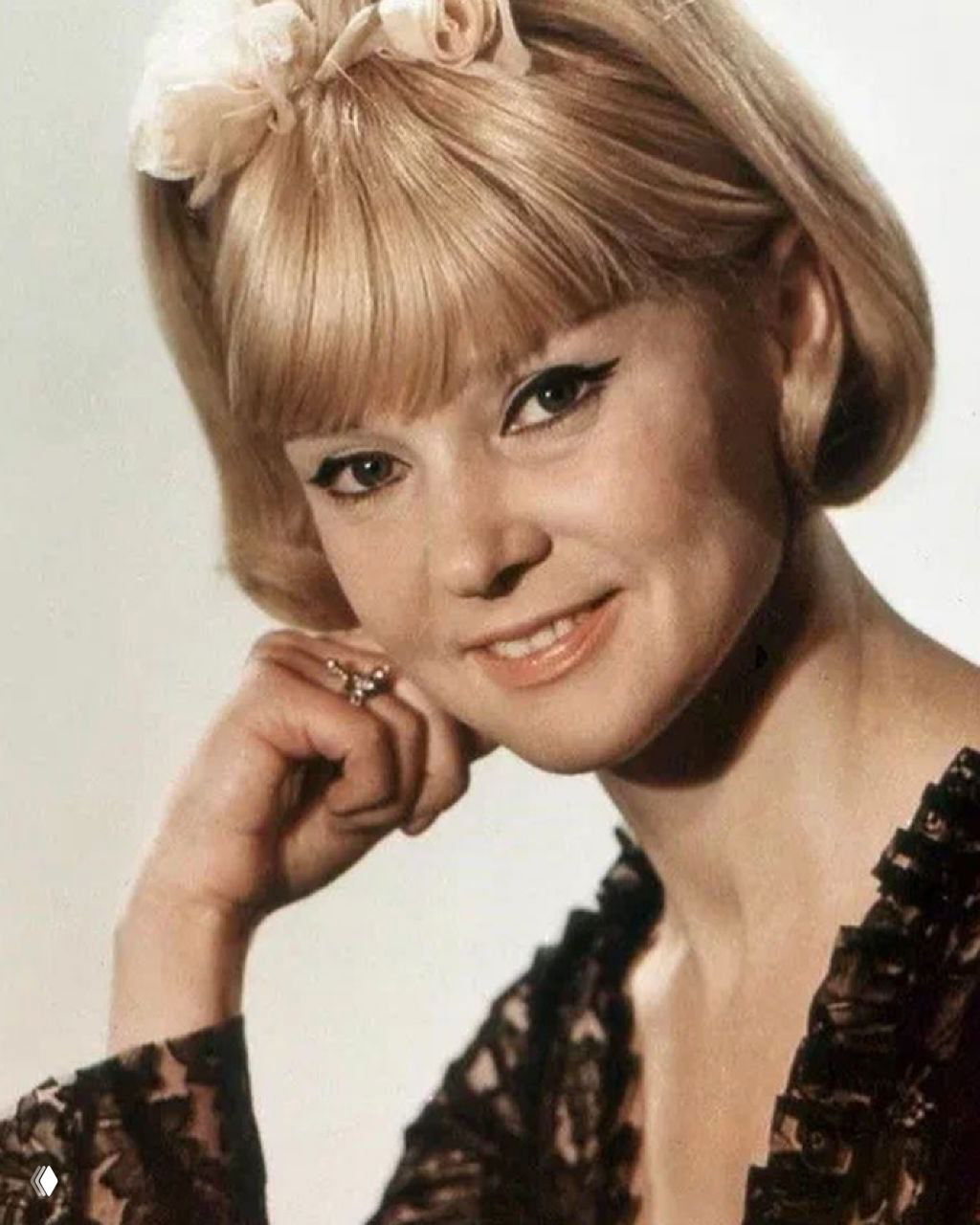 Женщина улыбается в бархатном тёмном платье и шляпе, портретная съёмка на нейтральном фоне; архивная фотография из фотосессии.