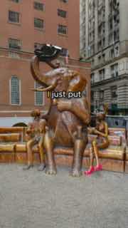 Статуя в городском сквере Нью‑Йорка с надетыми на неё кроксами; возле памятника виден человек и уличная сцена перформанса с элементами вирусного контента.